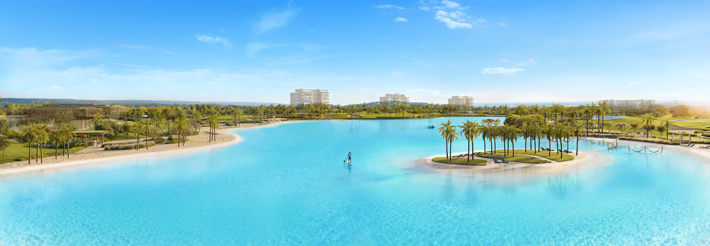 Panorama da lagoa cristalina do Heritage Riviera, com ilha de palmeiras e praia de areia